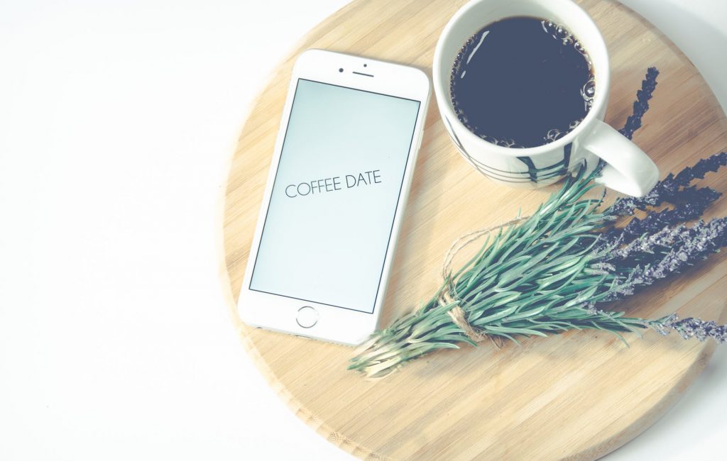 lavender and mug of coffee on small table near iphone