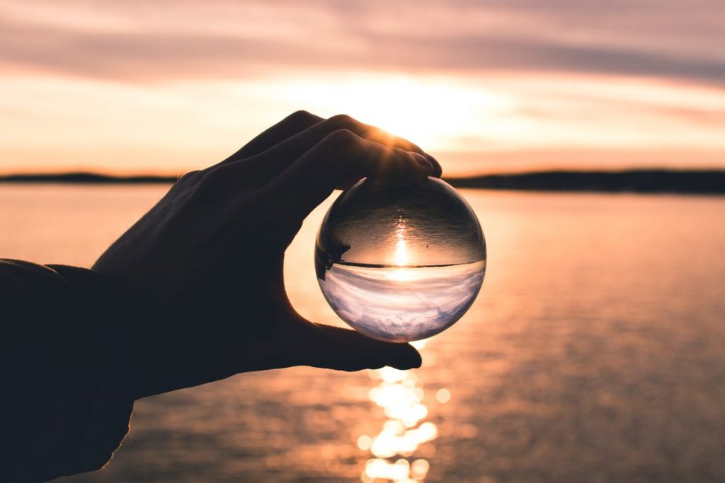 person holding glass sphere over water