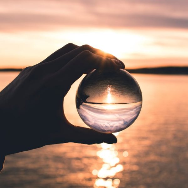 person holding glass sphere over water