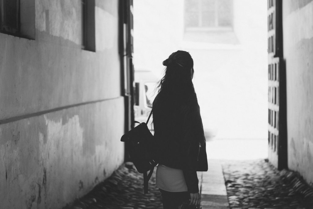 woman with backpack alone in alleyway black and white