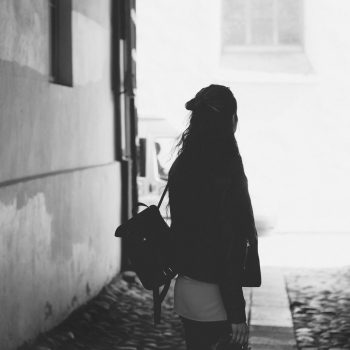 woman with backpack alone in alleyway black and white