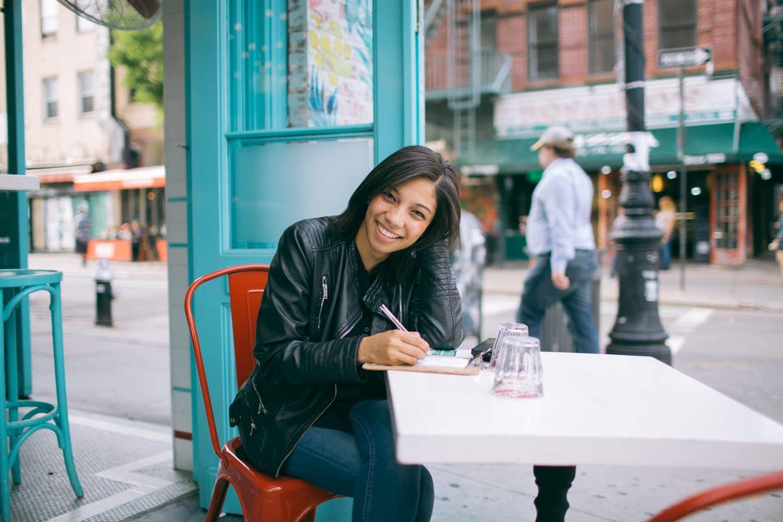 woman in black leather jacket sitting on red chair