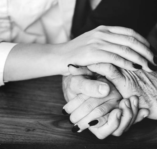 young woman holding elder's hand