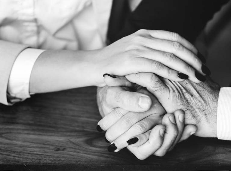 young woman holding elder's hand