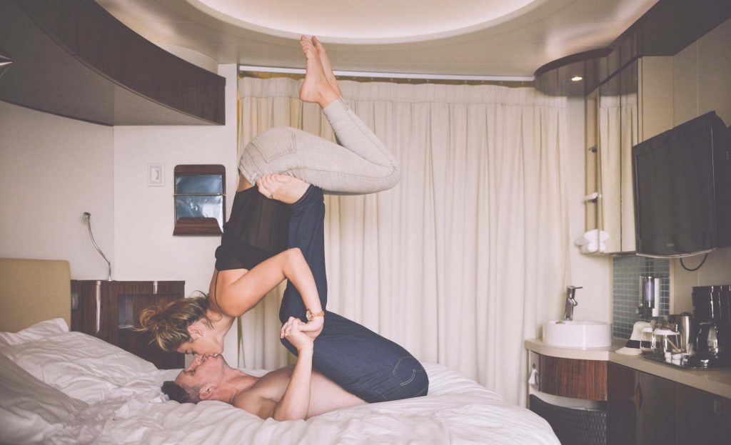 couple in bed kissing and doing AcroYoga