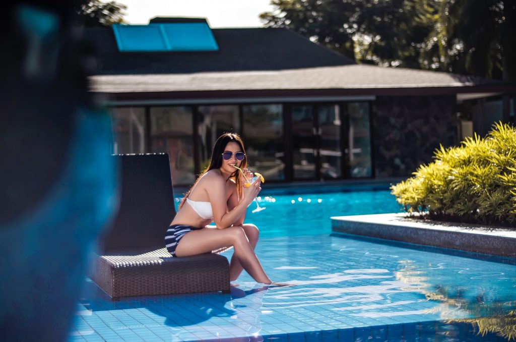 young woman drinking cocktail at a pool