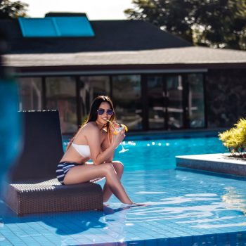 young woman drinking cocktail at a pool