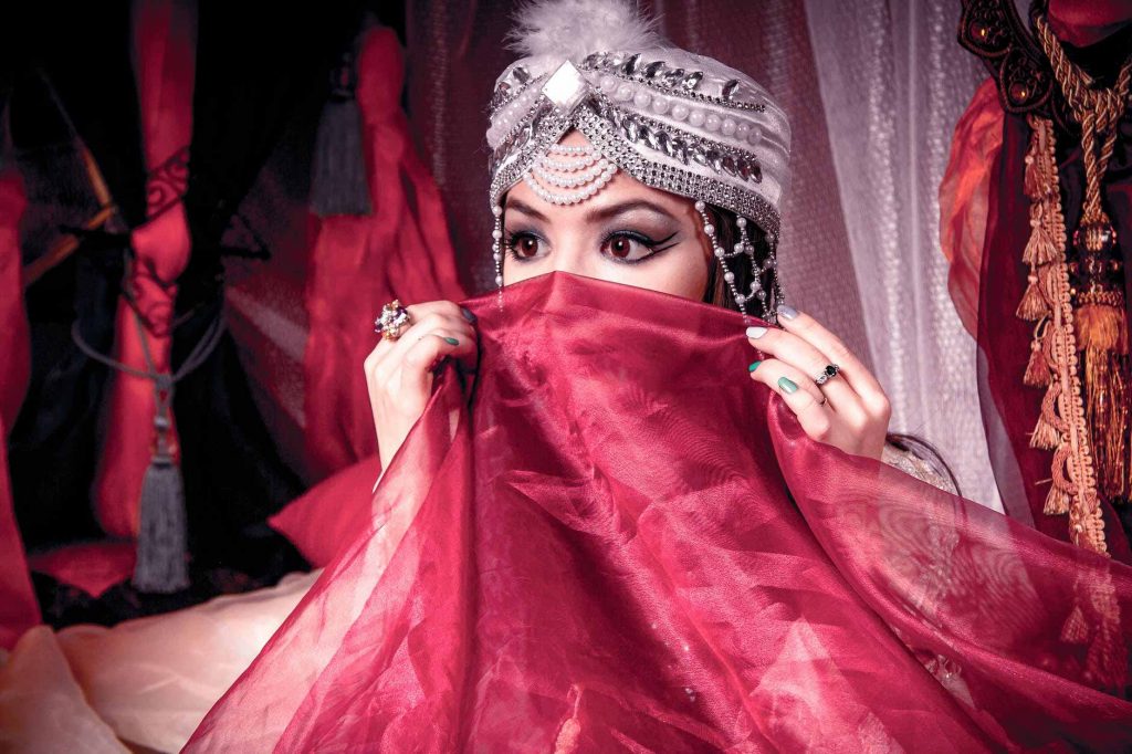 elaborately adorned woman covering face with veil